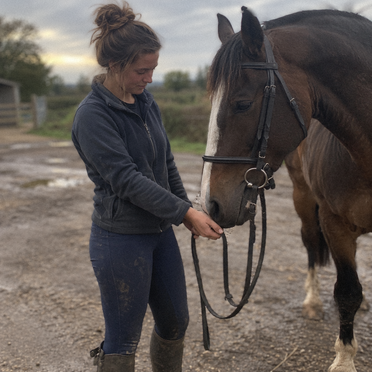 Charlotte standing with her horse in a stable yard